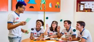 Imagem mostra alunos em atividade em escola NAVE. Eles seguram palitos de madeira. Foto: Carlos Fernando Guanabaratejo