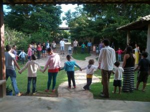 Imagem da reportagem mostra pais e crianças de mão dadas em roda. Crédito: Centro de referências em educação integral